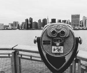 a metal object with a face on it by a body of water