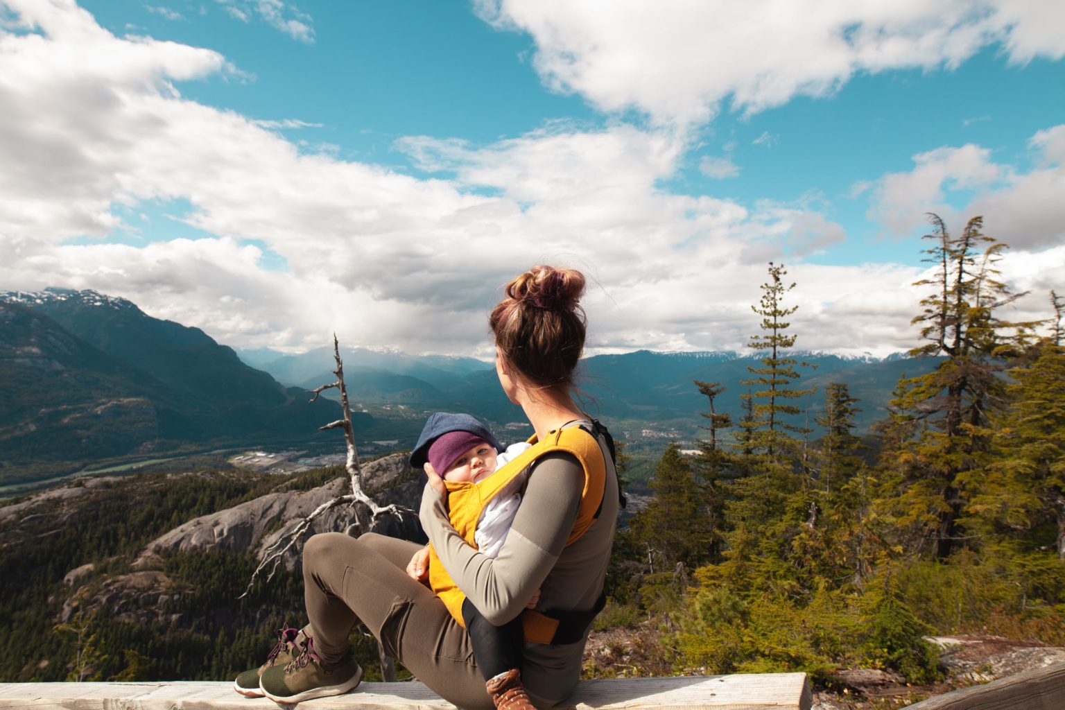a person and a child sitting on a rock looking at the view