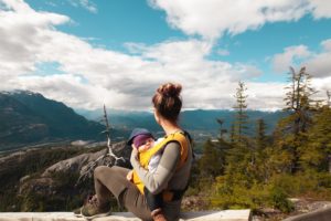a person and a child sitting on a rock looking at the view