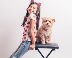 a girl sitting on a chair with a dog on her lap