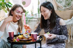 a couple of women sitting at a table with food and drinks