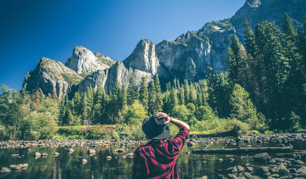 a person sitting on a rock overlooking a lake and mountains