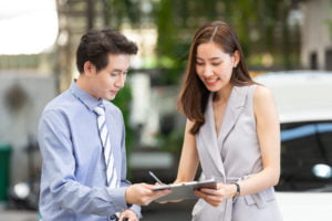 Customer woman signing on document paper for renting car or purchasing vehicle